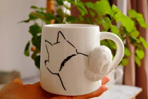 Detalle de taza de cerámica blanca con asa de cola de perro 3D y dibujo de Shiba Inu