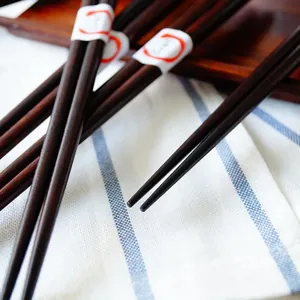 Baguettes japonaises en bois naturel avec logo de chat chanceux sur tissu rayé