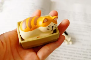 Mini sleeping ginger cat figurine on tray resting on an open book for home decor