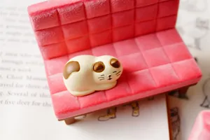 Calico cat figurine sitting on a pink velvet miniature sofa phone stand and ornament