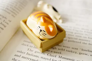 Miniature sleeping orange tabby cat resin figurine in a cozy desk storage box