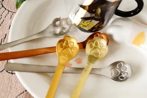 Close-up of cute cat paw coffee spoons in gold and silver finish on a white tray