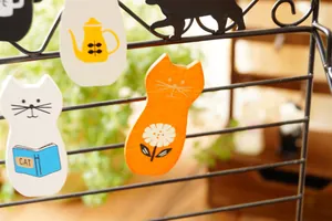 Set di 4 clip decorative in legno a forma di gatto appese a una griglia metallica nera