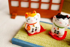 Set of 2 ceramic lucky cat figurines with red ribbon and golden bells on tatami mat
