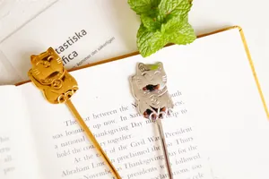 Close-up of gold and silver lucky cat stainless steel coffee spoons on an open book