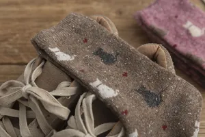 Close-up of retro knit cat socks in brown and pink paired with suede loafers