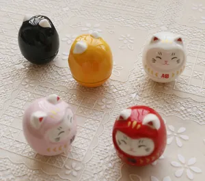 Top view of five colorful ceramic Maneki Neko Daruma figurines on a lace tablecloth