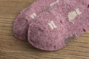 Macro view of thick knit pink cat pattern socks showing texture and animal silhouette