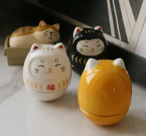 Close-up of mini ceramic Daruma fortune cat figurines with polished glaze finish