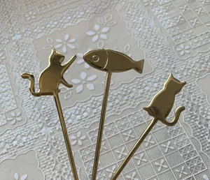 Macro shot of three gold metal cat and fish shaped dessert spoons on a lace tablecloth