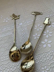 Detailed close-up of golden stainless steel spoons with cute cat and fish handle designs