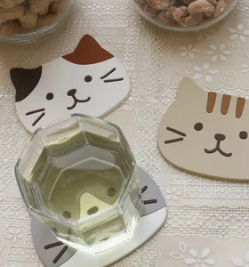 Cute cartoon cat silicone coasters in calico and tabby patterns on a lace tablecloth