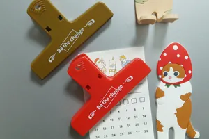 Dettaglio di clip magnetiche in plastica colorata e ganci a gatto su calendario