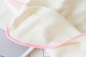Close-up of soft white coral fleece fabric with delicate pink stitched edges