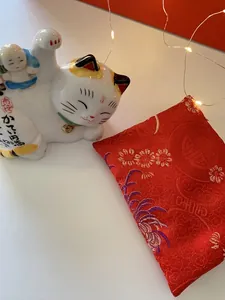Japanese ceramic Maneki Neko lucky cat figurine with a red embroidered silk cushion
