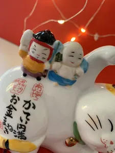 Ceramic Maneki Neko lucky cat figurine with traditional Japanese Seven Lucky Gods motifs