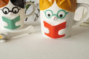 Detail view of 3D embossed calico cat ceramic mug with cute glasses and a matching spoon