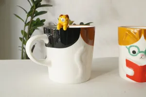 Detailed view of ceramic calico cat mug with 3D tail handle and climbing kitten figurine