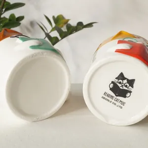 Decole Reading Cat ceramic mug base with cute calico cat illustration and brand logo