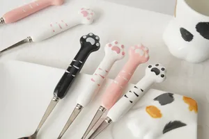 Détail des cuillères en acier avec manche en céramique patte de chat et tasses assorties