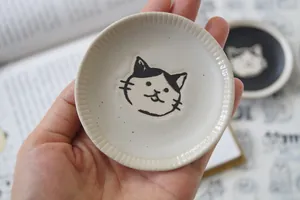 Detailed view of hand-painted cat face on stoneware dip saucer with ribbed edges