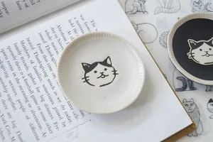 Detail of hand-painted ceramic cat-shaped sauce dishes with embossed radial striped edges