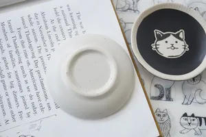 Macro view of hand-painted ceramic cat saucers with artistic stoneware texture