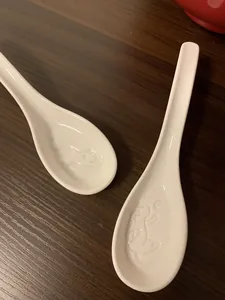 Close-up of white ceramic soup spoons featuring 3D cat silhouette relief pattern