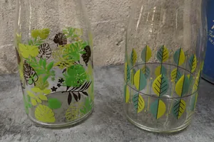 Détail de carafes en verre avec motifs botaniques de feuilles et de monstera