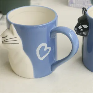 Close-up of light blue ceramic mug featuring 3D white cat relief and white heart pattern