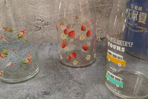 Détail de carafes en verre avec motifs fraises, fleurs et bus vintage pour boissons froides