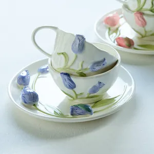Juego de taza y plato de cerámica con relieve de tulipán azul y acabado blanco lechoso