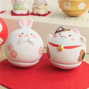 Detailed view of hand-painted ceramic rabbit and Maneki-neko lucky cat tumbler figurines
