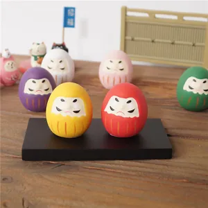 Gros plan de figurines Daruma en céramique colorées sur socle en bois traditionnel