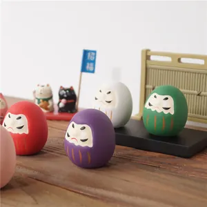 Poupées traditionnelles japonaises Daruma en céramique de diverses couleurs sur bois