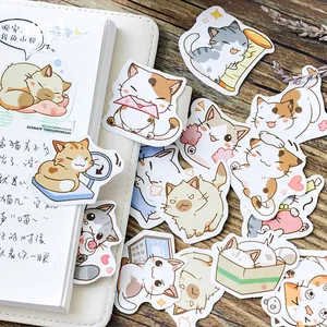 Set of 45 cute cartoon cat stickers for journals on a white notebook and wood desk