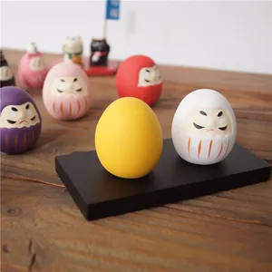 Figurines japonaises Daruma minimalistes de couleurs assorties sur un bureau en bois