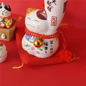 Estatua Maneki Neko japonesa de cerámica en cojín rojo para la prosperidad