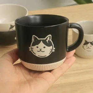Detail of hand holding a black ceramic cat mug with vertical striped non-slip base