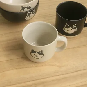 Close-up of a Japanese ceramic cat mug with vertical anti-slip stripes on a wooden desk