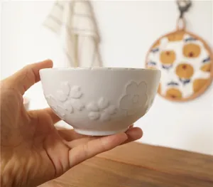 Detailed close-up of a Japanese ceramic bowl featuring embossed cherry blossom textures