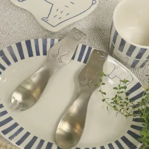 Macro detail of bear-shaped stainless steel dessert spoon and fork with matte brushed finish