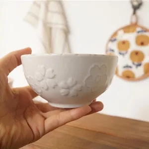 Japanese style ceramic rice bowl with embossed cherry blossom patterns and ivory glaze