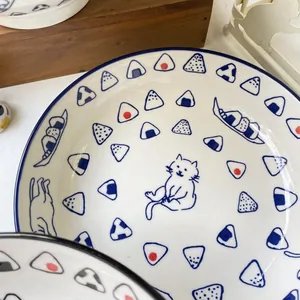 Detail of round ceramic sushi plate featuring a hand-drawn cat and rice ball patterns