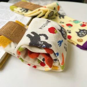 Dettaglio calzini in cotone beige con divertenti stampe di gatti e fragole con etichetta