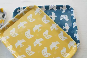Close-up of yellow and blue penguin trays with minimalist bird and dot patterns