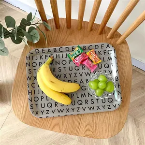Cute gray penguin alphabet tray on a wooden seat with fresh fruits and candies