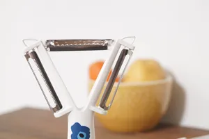 Détail macro d'un éplucheur 3-en-1 en acier inoxydable avec motif floral sur le manche