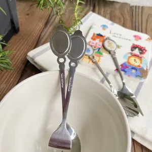 Detailed close-up of retro cat-themed stainless steel dessert spoon and fork set