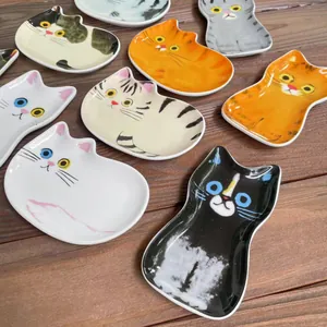 Varietà di ciotole per condimenti in ceramica a forma di gatto su un tavolo in legno